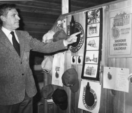 Tom Baird pointing to collection of centennial memorabilia