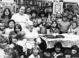 A lady celebrating her 100th birthday with some children in the library. Belleville, Ontario.